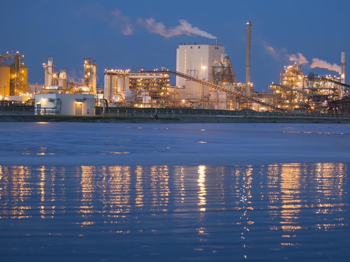 The Marlboro Mill sits beside a body of water at twilight with its lights on.