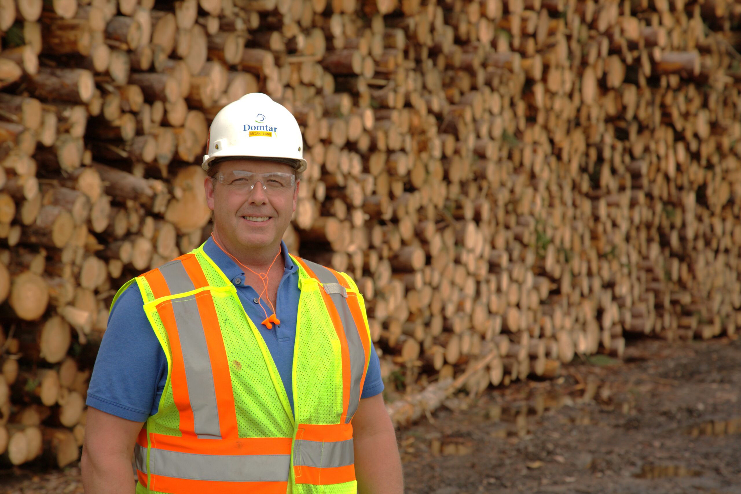 Person in safety gear standing in front of wood products