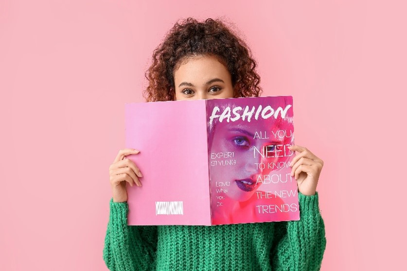 young woman peeking over the cover of a magazine